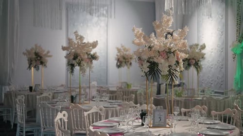 Luxurious restaurant with beautifully arranged round tables, tall floral centerpieces, and refined