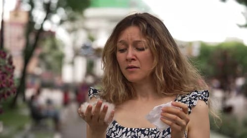 Young Woman Holds Poplar Wool Handful and Sneeze on Street