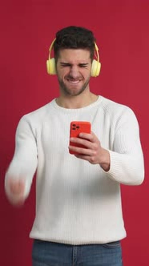 Young Man with Smartphone and Headphones Celebrates Success