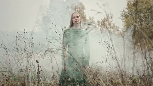 Model posing in green dress with autumn fog behind her