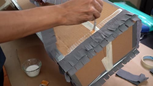 Taping gray arts paper on cardboard box, paper crafts