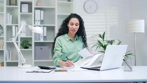 young female employee prepares for a presentation remotely and talks online via video call with coll