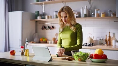 Woman Prepares Healthy Salad Using Tablet in Kitchen