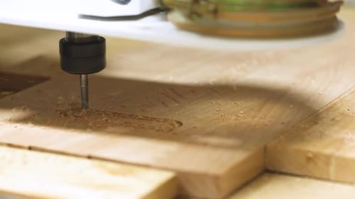 CNC cutting wooden board in closeup image. Homemade CNC working on the wooden board.