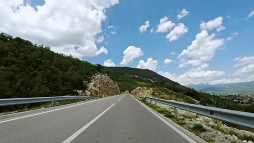 First Person POV Driving Along a Rural Motorway Through a Mountain Pass with Rocky Defiles in the