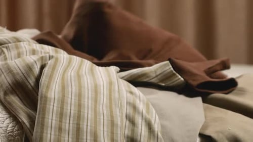 Clothing Items Dropped onto Quilted Bed