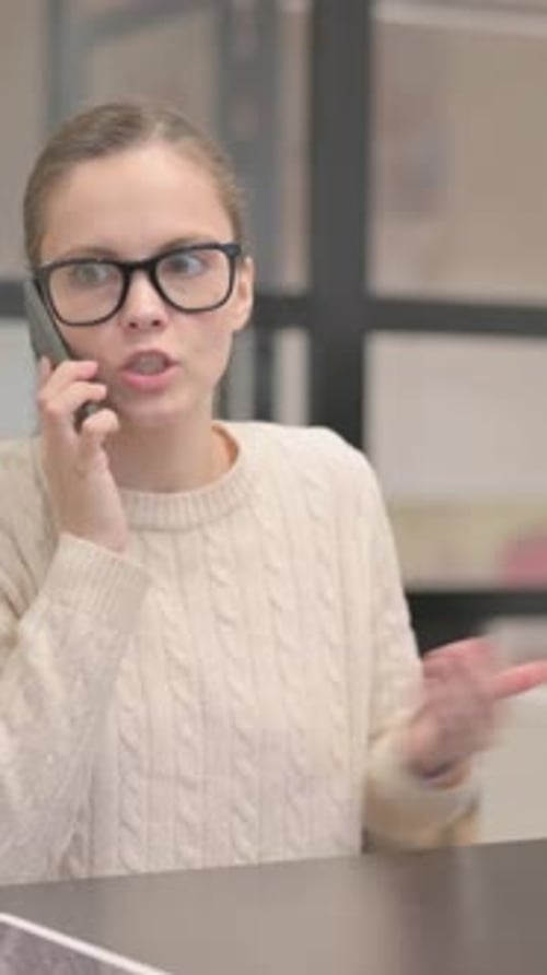 Woman in Glasses Talking on Phone at Desk