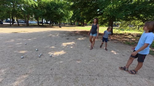 Family Playing Petanque Together in the Park Adults and Children Take Turns Throwing Metal Balls on