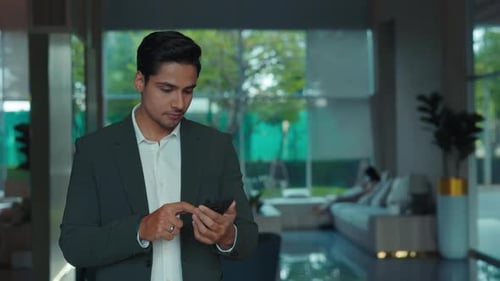 Portrait of Joyful Indian Man in Suit Uses Smartphone Stock Market App in Office