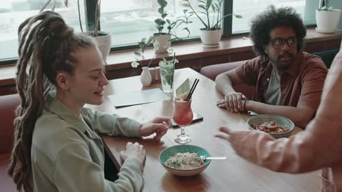 Friends Thanking Waitress for Good Service as She Placing Plates on Cafe Table