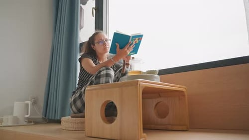 Woman Studying with Tea Nearby Cozy Hillside Hotel with Writing Space Tranquil Hotel Nook Offering
