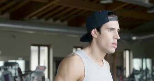 A guy in the gym to stay fit and have defined muscles or lose weight runs on the treadmill with a