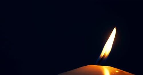 Eine
einzelne große gelbe Kerzenflamme leuchtet und erlischt, isoliert auf schwarzem Hintergrund. Zeitlupe und