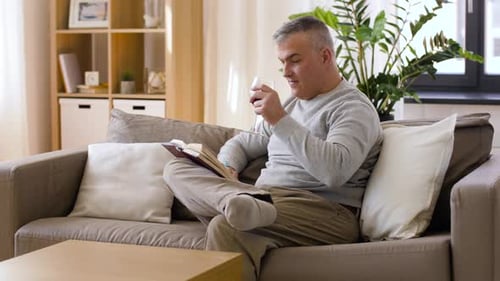 Man Reads Book and Drinks Wine at Home