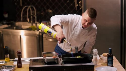 Close Up Chef Frying Different Vegetables on a Hot Frying Pan with Torch on the Stove