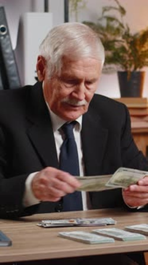 Reicher kaukasischer Senior-Geschäftsmann, der Geld zählt, Bargeld, Gewinn, Einkommen, Gewinn zu Hause berechnet