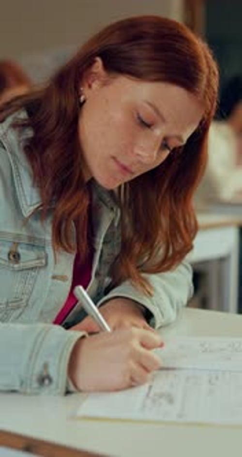 Teenage girl writing in classroom