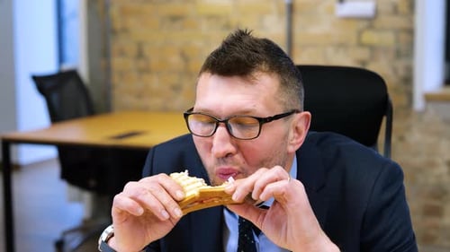 Adult Man Eating a Sandwich in Office