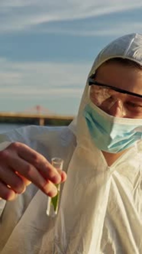 Scientist in Protective Suit Holds Test Tube