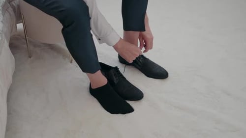 Man Tying Dress Shoes on Fluffy White Carpet
