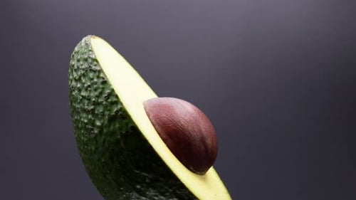 CLOSE UP SHOT OF AN AVOCADO ROTATING ON A BLACK BACKDROP
