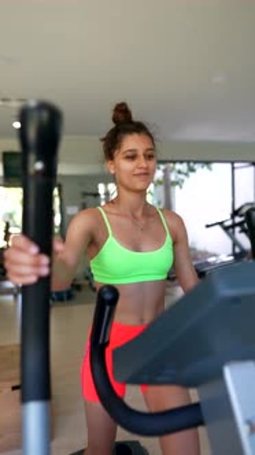 A Young Woman is Exercising on an Elliptical Trainer in a Contemporary Gym Environment