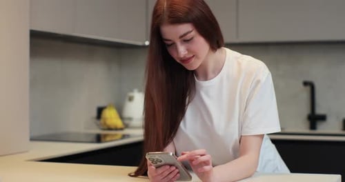 Woman Using Smartphone in Modern Kitchen