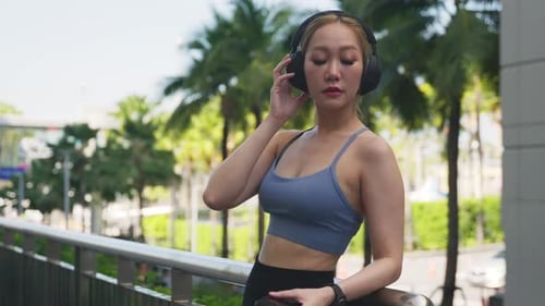 Young Woman Athlete Lifestyle Practices Yoga Sport Exercise in City Wearing Headphones and Using