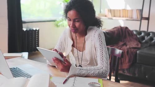 Young African American Woman Works with Laptop and Tablet at Same Time