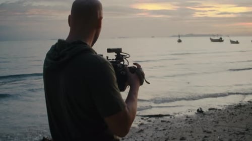 Filmmaker Shooting Video at Beach During Sunrise