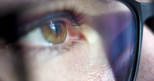 Close-up macro shot of young female human brown eye with vision glasses blinking in slow motion. C