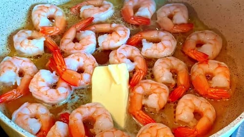 Cooking delicious shrimp with butter in hot pan, close up