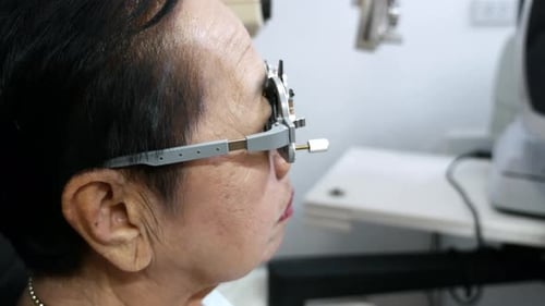 Eine ältere Frau, die ihre Augen von einem Optiker in einer optischen Klinik in einem gründlich untersuchen lässt