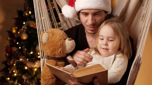 Father and Daughter Read Christmas Story in Hammock