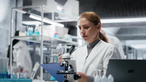 Scientist Examining Samples and Taking Notes in Lab