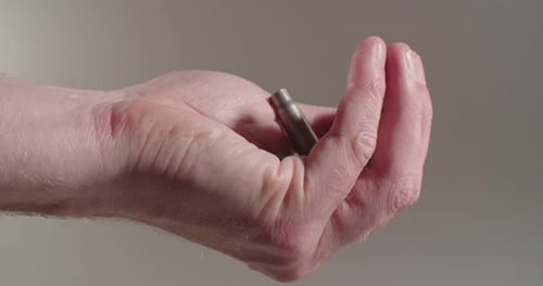 Close-up of cartridge shells landing and bouncing out of a human hand.