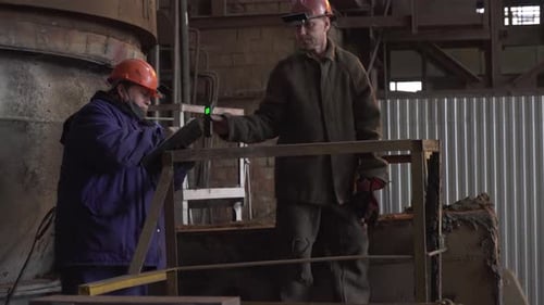 Men Inspecting Factory Equipment Indoors