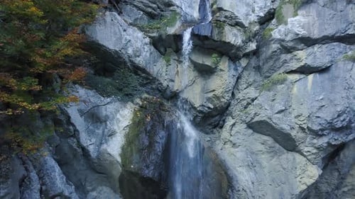 drone flying backwards, facing towards a waterfall in the austrian alps