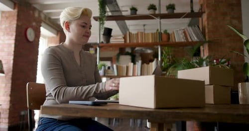 Woman Working at Desk with Laptop and Boxes