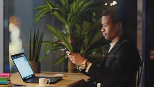 African American Office Executive Man Using Smartphone Application and Pc Laptop Computer at Desk in