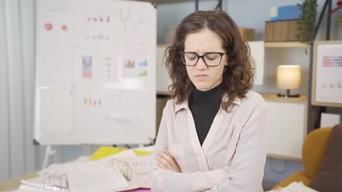 Worried Woman Standing in Office with Arms Crossed