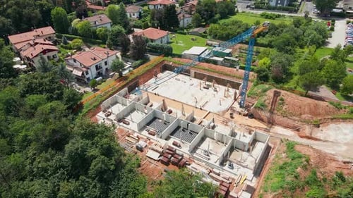 Sitio de construcción residencial con torre de grúa rodeado de villas con jardines verdes en el norte