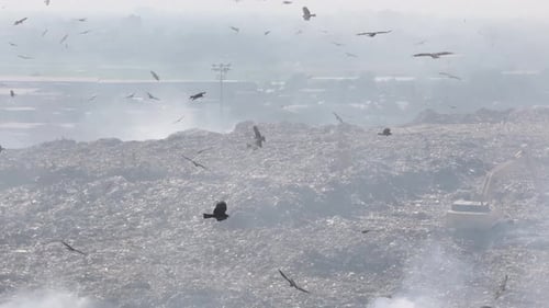 Aerial view of polluted landfill with debris and smoke, Bangladesh.