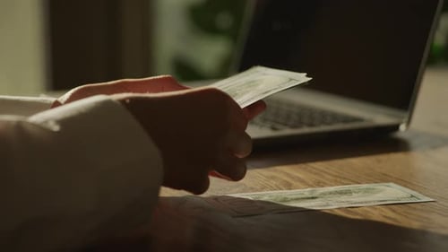 Hands Counting Cash Money by Laptop Computer