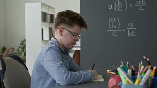 Portrait of Smiling Boy with Glasses Working on Math Equations in School
