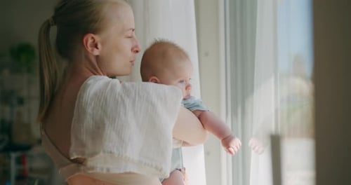 Woman Holding Baby Looking Out Window