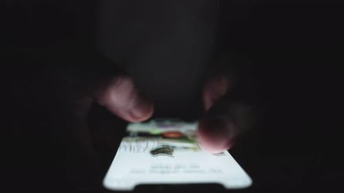 Close-up of Hands Scrolling on Smartphone at Night