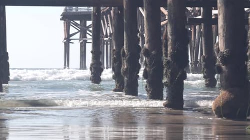 Below Wooden Crystal Pier on Piles Ocean Beach Water Waves California USA