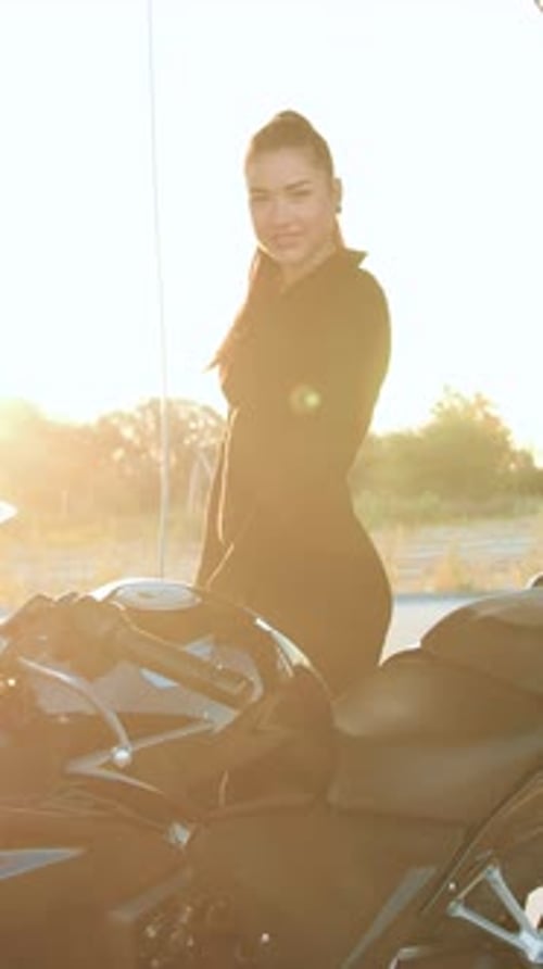 Smiling Woman with Ponytail Poses Beside Black Motorcycle