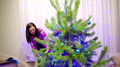 Woman Decorating Christmas Tree at Home